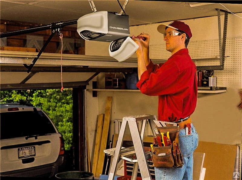 Technician on a ladder installing a garage door opener in a garage