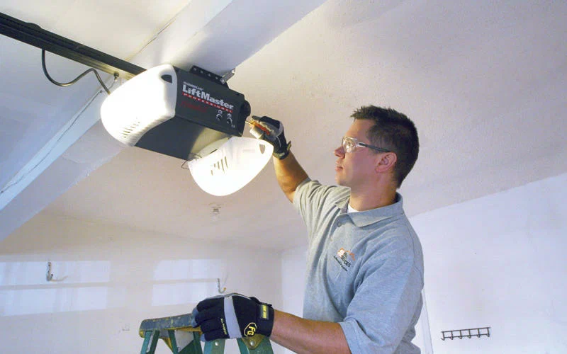 Professional adjusting garage door opener on the ceiling
